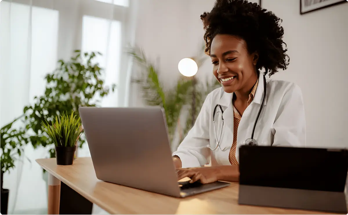 Woman doctor smiling while using laptop for interview preparation